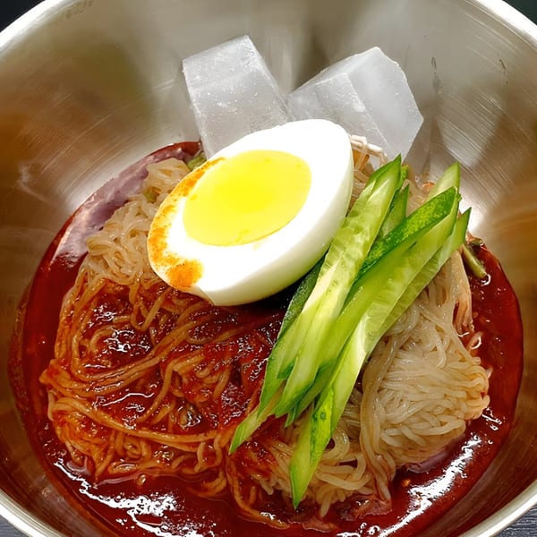 Macheko's Korean cold noodles with spicy sauce, cucumber, a hard-boiled egg, and ice cubes.