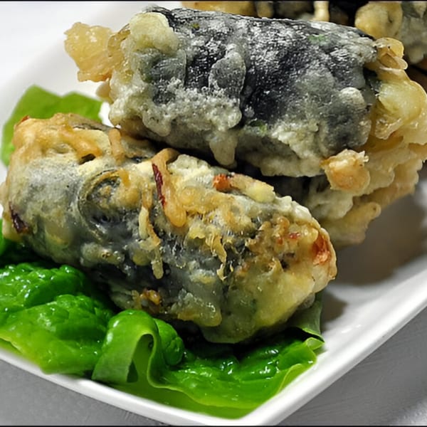 Two pieces of Korean fried seaweed rolls (gimmari) on a white plate with green lettuce.