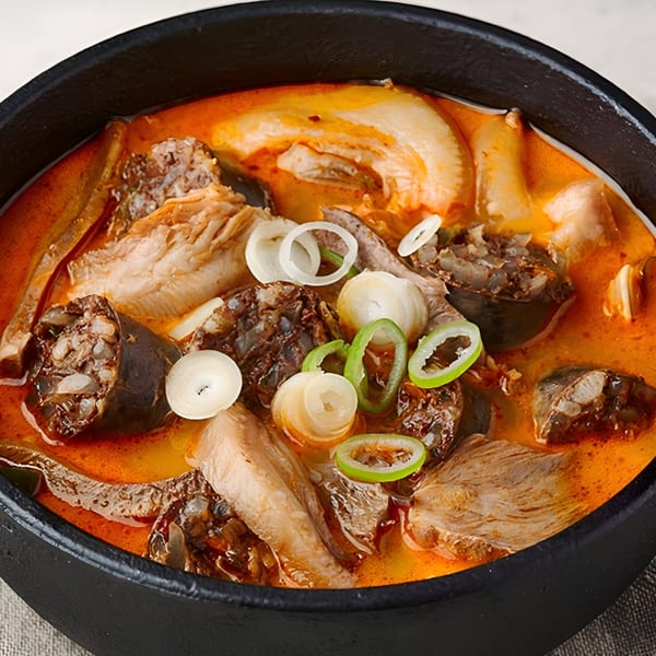 Close-up of Macheko's Korean sundae guk, a rich red stew with blood sausage, meat, and vegetables.